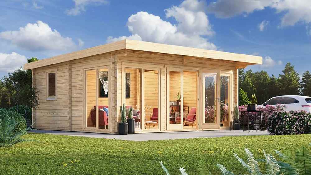 A wide-angle view of the GardenHouse24 USA Taunus 70 Garden Room shows it placed in a green lawn with modern furnishings inside and flower beds around