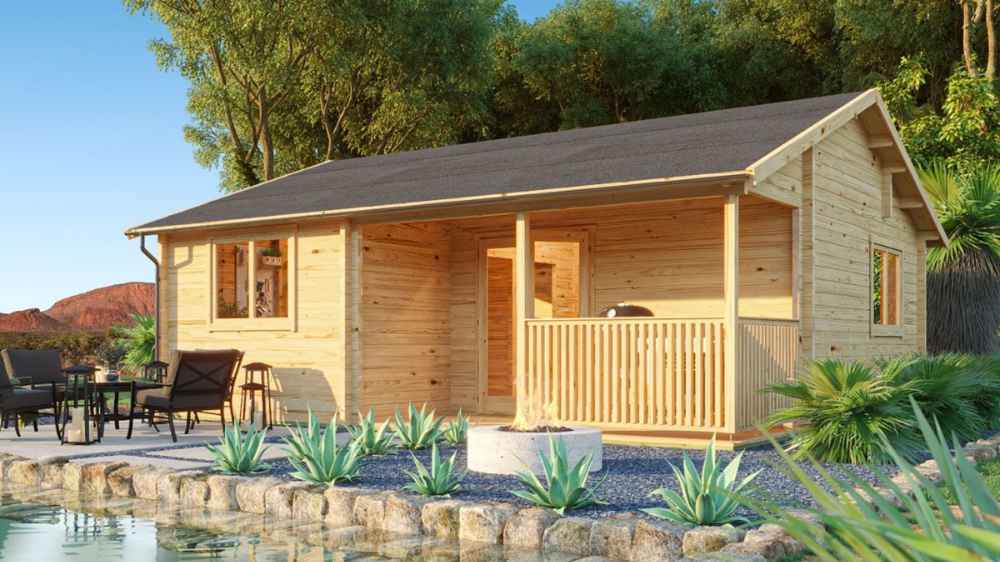 A wooden lakeside cabin with a cozy front porch and patio furniture surrounded by lush greenery is the Sawmill Structures The Sunbeam Lakehouse 70mm Garden Room
