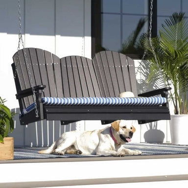 A black Adirondack swing on a porch is fitted with a blue-striped LuxCraft 5 Seat Cushion above a relaxed dog lying on a cozy rug