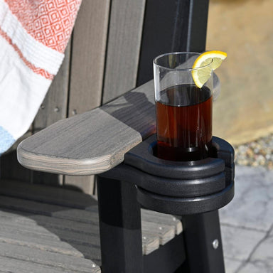 A black LuxCraft Stationary Cup Holder attached to the arm of a grey outdoor chair, with a drink resting securely inside.