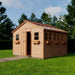 A bright, fresh-looking Outdoor Living Today 12×12 Sunshed Garden Shed stands on green grass, with its door ajar and sunlight reflecting off its many clear roof panels