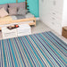 A bright indoor room with a daybed and white furniture features the Couristan Cape Indoor/Outdoor Rug - Brockton/Cobalt-Teal bringing color and warmth to the floor