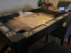 A cat lounges on the Game Theory Tables Origins Lit Game Table, which features a recessed playing area with cup holders and space for game accessories