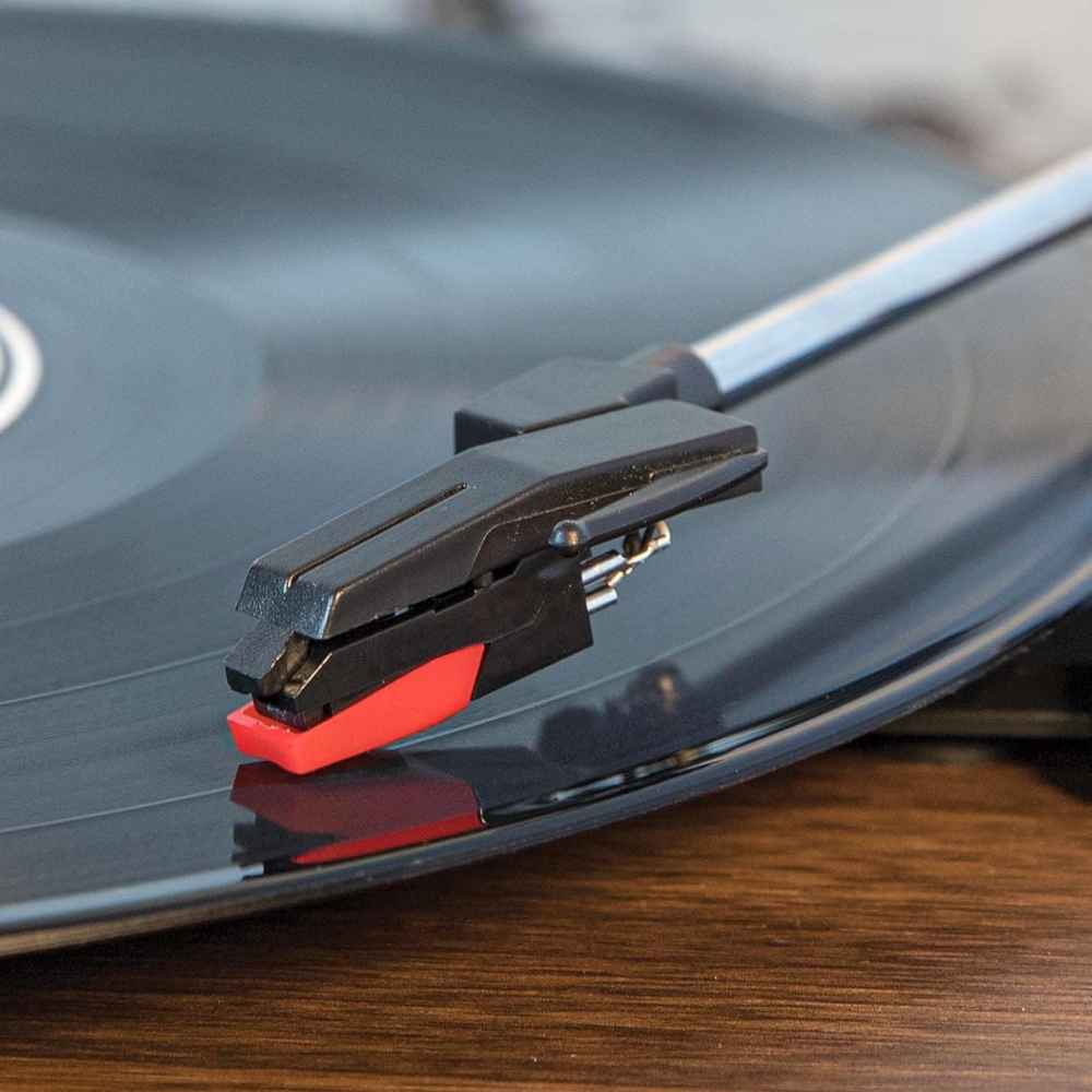 A close-up of a Crosley NP16 Replacement Needle mounted on a turntable playing a vinyl record