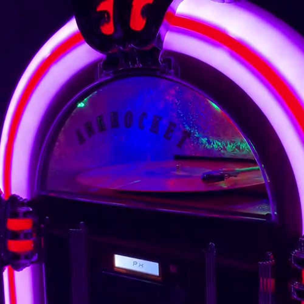 A close-up of the Arkrocket Taurus II Jukebox with Stand - Black 2024 New Upgrade highlighting its bright neon-like red and purple LED lights