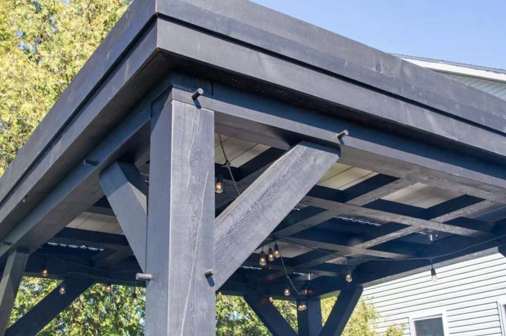 A close-up of the Brookside Timber Frame Zion Resort Pergola highlights the sturdy black wooden beams and intricate construction details