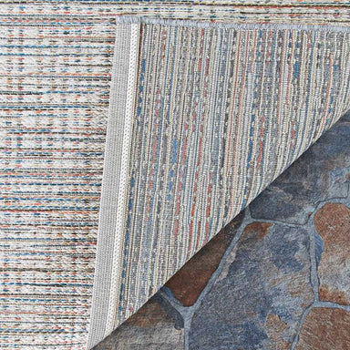 A close-up of the Couristan Cape Indoor/Outdoor Rug - Falmouth/Ivory-Coral with one corner flipped to show the detailed weave and backing material