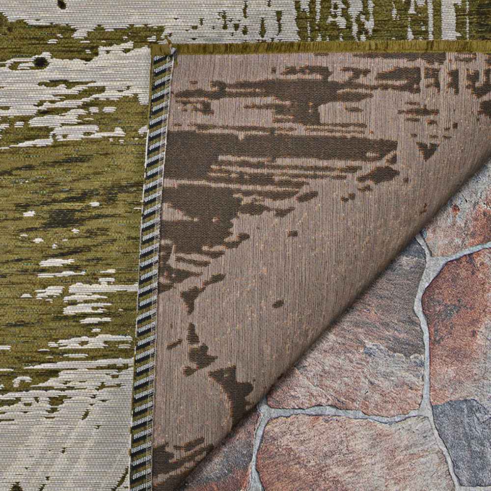 A close-up of the Couristan Castille Indoor/Outdoor Rug - Canvas/Tea Leaf shows its detailed weave, earth-toned pattern, and the backing layered over stone tiles