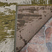 A close-up of the Couristan Castille Indoor/Outdoor Rug - Canvas/Tea Leaf shows its detailed weave, earth-toned pattern, and the backing layered over stone tiles