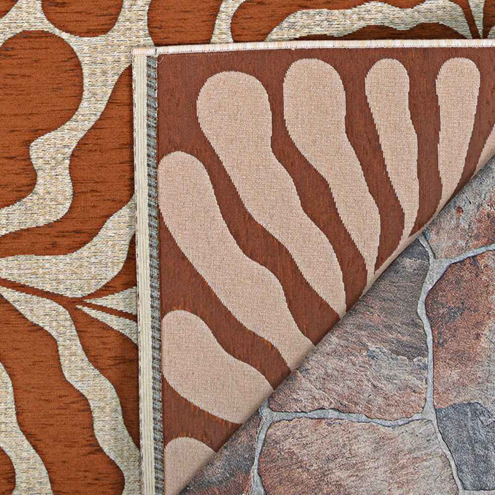 A close-up of the Couristan Castille Indoor/Outdoor Rug - Fiore/Terra-Cotta shows its reversible design with organic beige and terracotta patterns on both sides