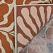 A close-up of the Couristan Castille Indoor/Outdoor Rug - Fiore/Terra-Cotta shows its reversible design with organic beige and terracotta patterns on both sides