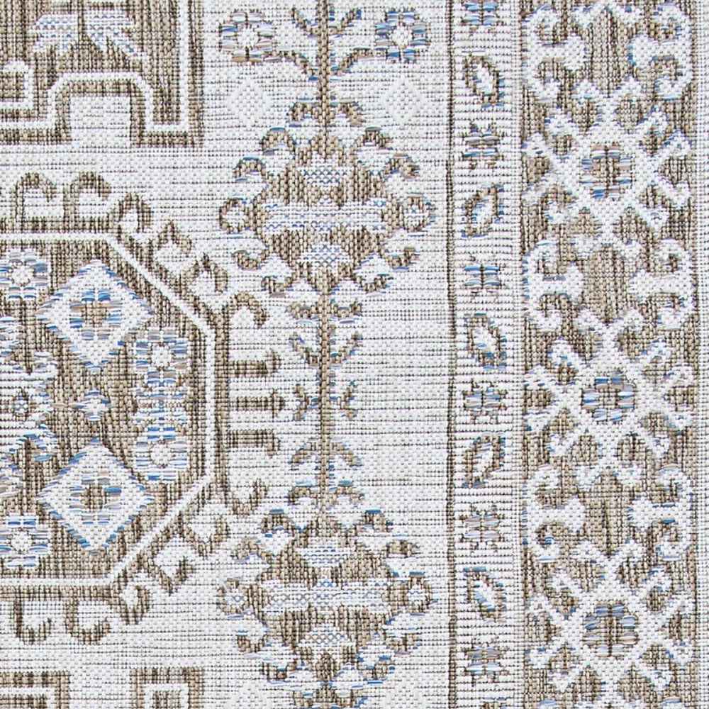 A close-up of the Couristan Charm Indoor/Outdoor Rug - Woodburn/Ivory-Sand highlights its woven texture and intricate geometric floral design