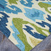 A close-up of the Couristan Covington Indoor/Outdoor Rug - Delfina/Azure-Lemon shows its thick looped texture with blue, green, and ivory abstract patterns on stone flooring