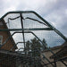 A close-up of the black mesh roof on the Outdoor Living Today 8×12 Raised Garden Bed shows the frame arching over the garden against a cloudy sky
