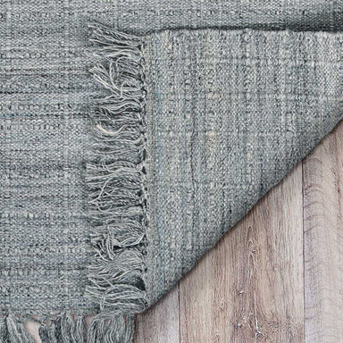 A close-up of the corner and fringe detail of the Couristan Ascot Indoor/Outdoor Rug - Windowpane/Tweed shows its textured weave and tightly bound edge