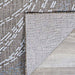 A close-up of the corner of the Couristan Charm Indoor/Outdoor Rug - Aurora/Twig shows its durable woven texture and non-slip backing flipped over on a wooden floor