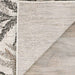 A close-up of the corner of the Couristan Charm Indoor/Outdoor Rug - Kimberly/Naturals is lifted to show its textured, durable underside on wood flooring