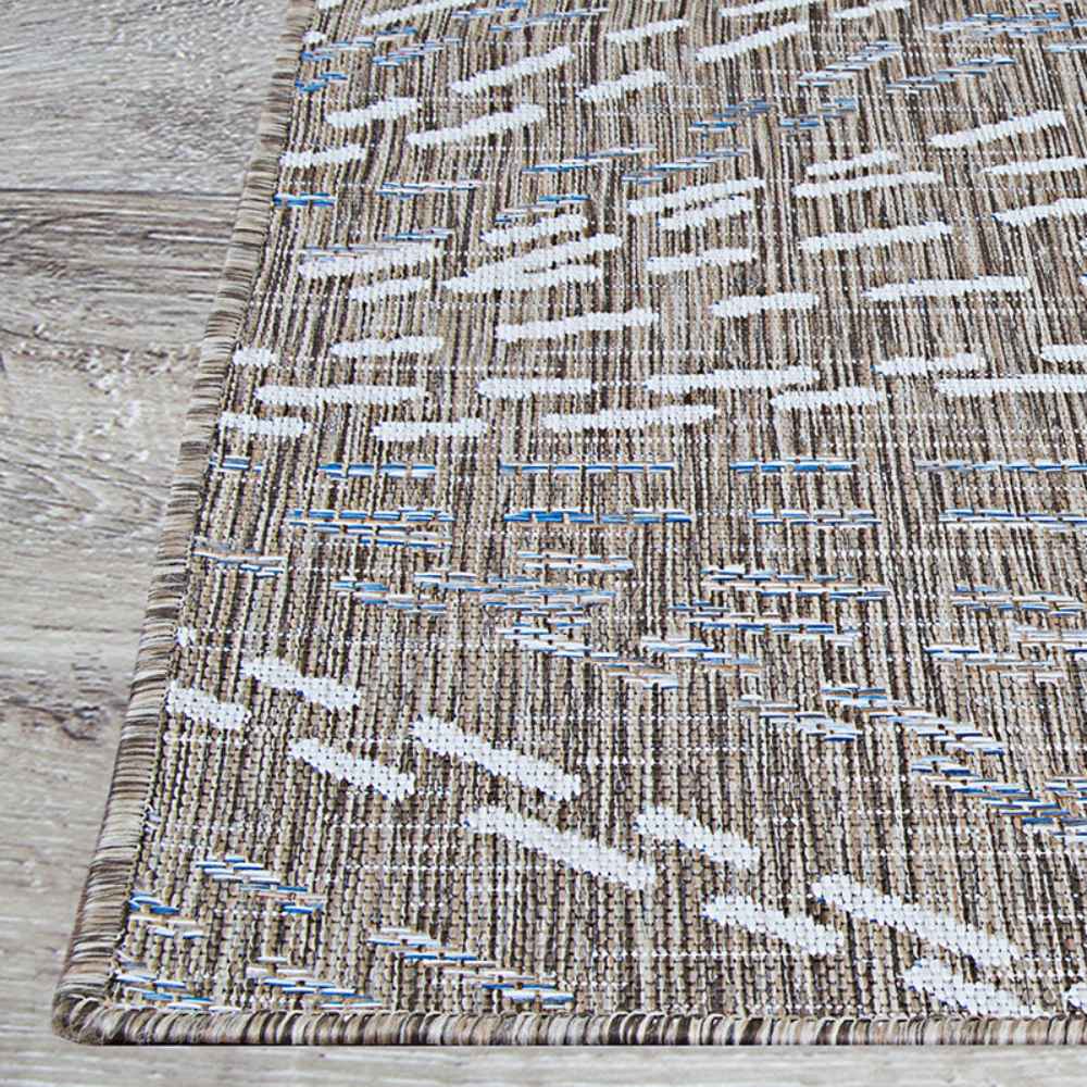 A close-up of the edge of the Couristan Charm Indoor/Outdoor Rug - Aurora/Twig showcases its tightly bound border and intricate patterned surface