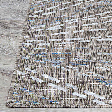 A close-up of the edge of the Couristan Charm Indoor/Outdoor Rug - Aurora/Twig showcases its tightly bound border and intricate patterned surface