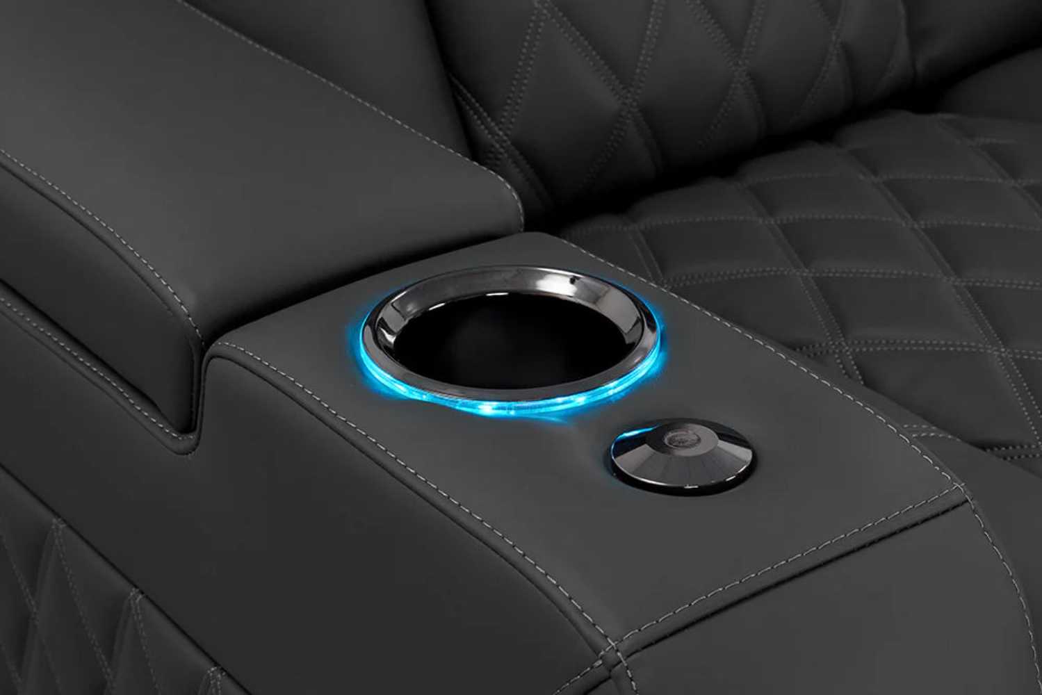 A close-up of the graphite Valencia Tuscany XL Luxury Edition Home Theater Seating with a blue LED-lit cup holder and sleek stitching