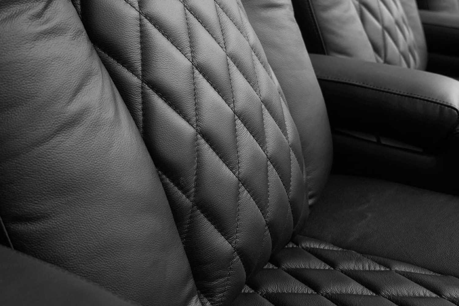 A close-up of the midnight black Valencia Tuscany XL Console Edition Home Theater Seating showcases its luxurious diamond-stitched leather upholstery