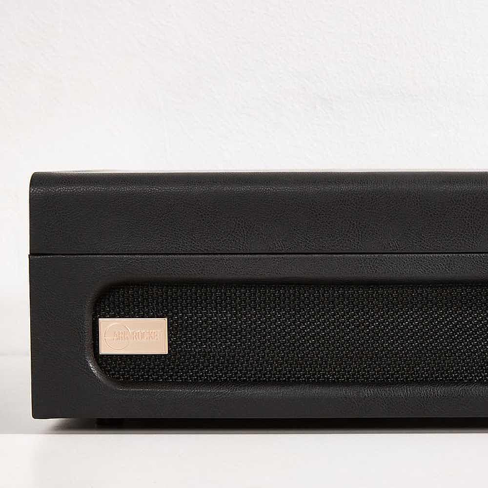 A close-up of the speaker front of Arkrocket Coryphaeus Bluetooth Turntable Deluxe Edition Record Player (BlackGreen) with a small gold label and black mesh speaker grille