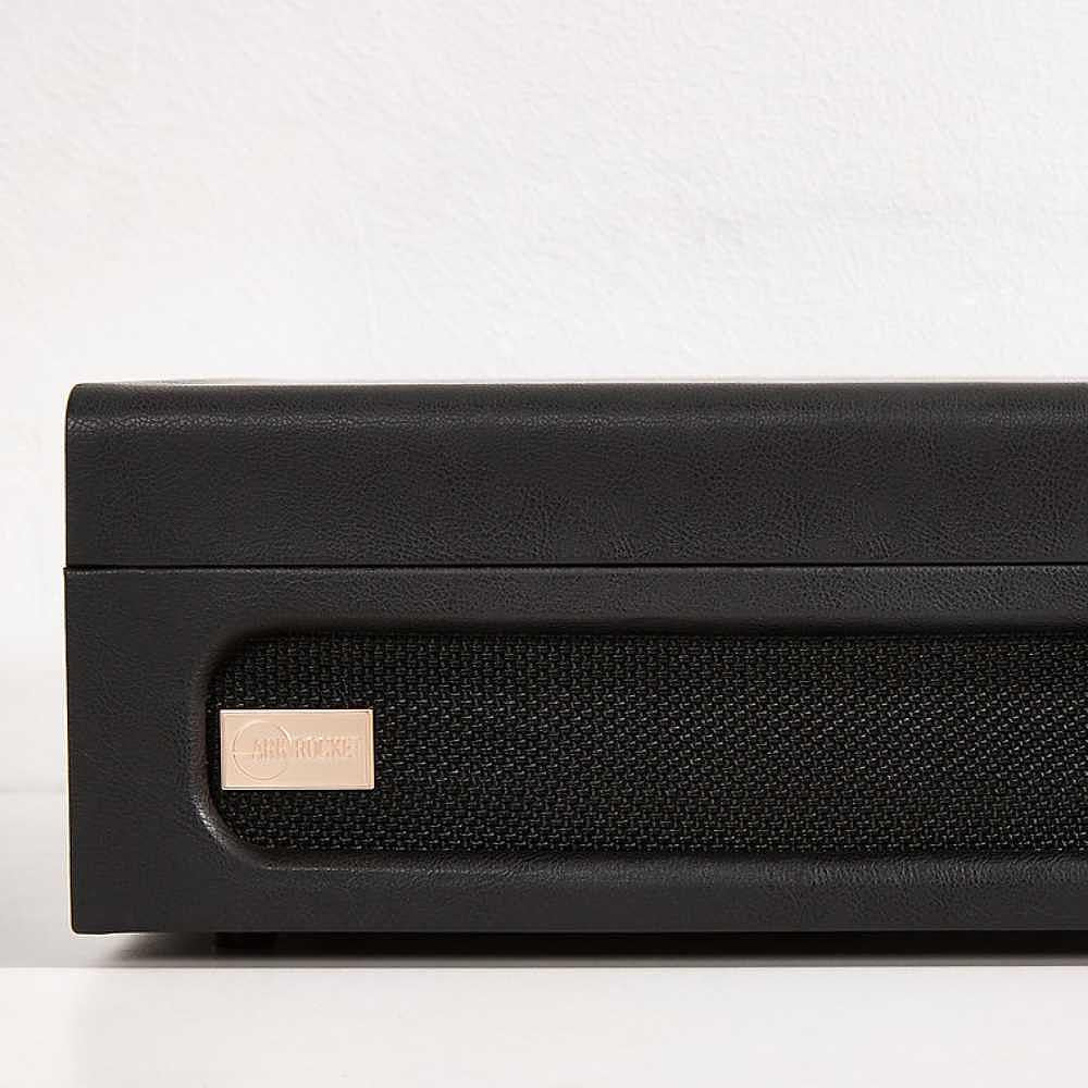 A close-up of the speaker grill and small gold label on the Arkrocket Coryphaeus Bluetooth Record Player with Record Storage Case (BlackGreen)