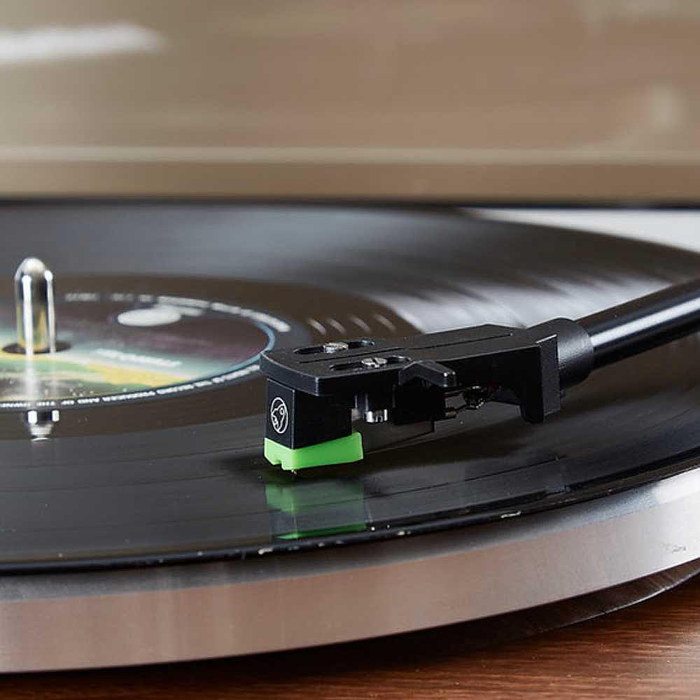 A close-up of the stylus and tonearm of Arkrocket Huygens Bluetooth Turntable with Built-in Speakers (Walnut) resting on a spinning vinyl record