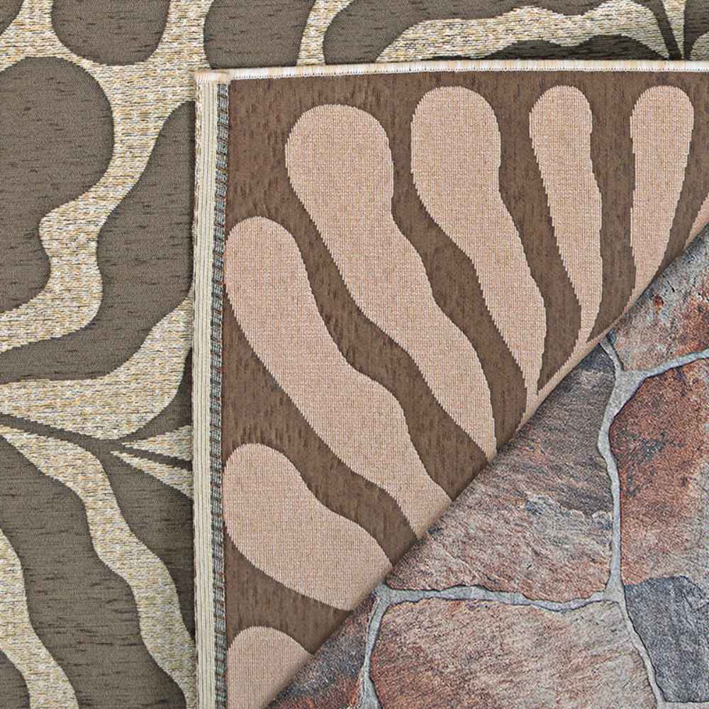 A close-up view of the Couristan Castille Indoor/Outdoor Rug - Fiore/Mocha shows its mocha and beige swirl design flipped over on a stone patio