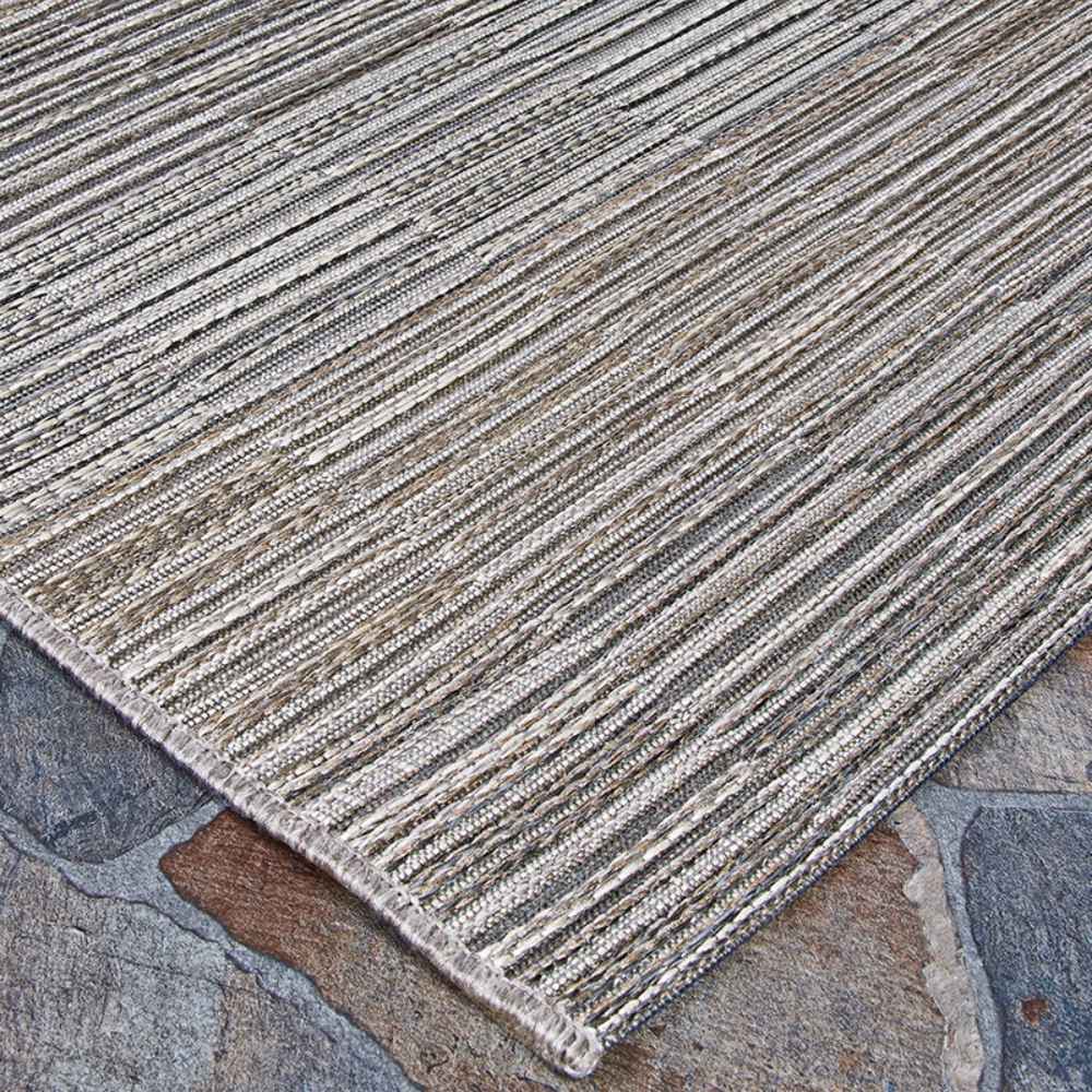 A corner angle shot of the Couristan Cape Indoor/Outdoor Rug - Fayston/Silver-Charcoal emphasizes the natural and silver tones woven into its clean edges