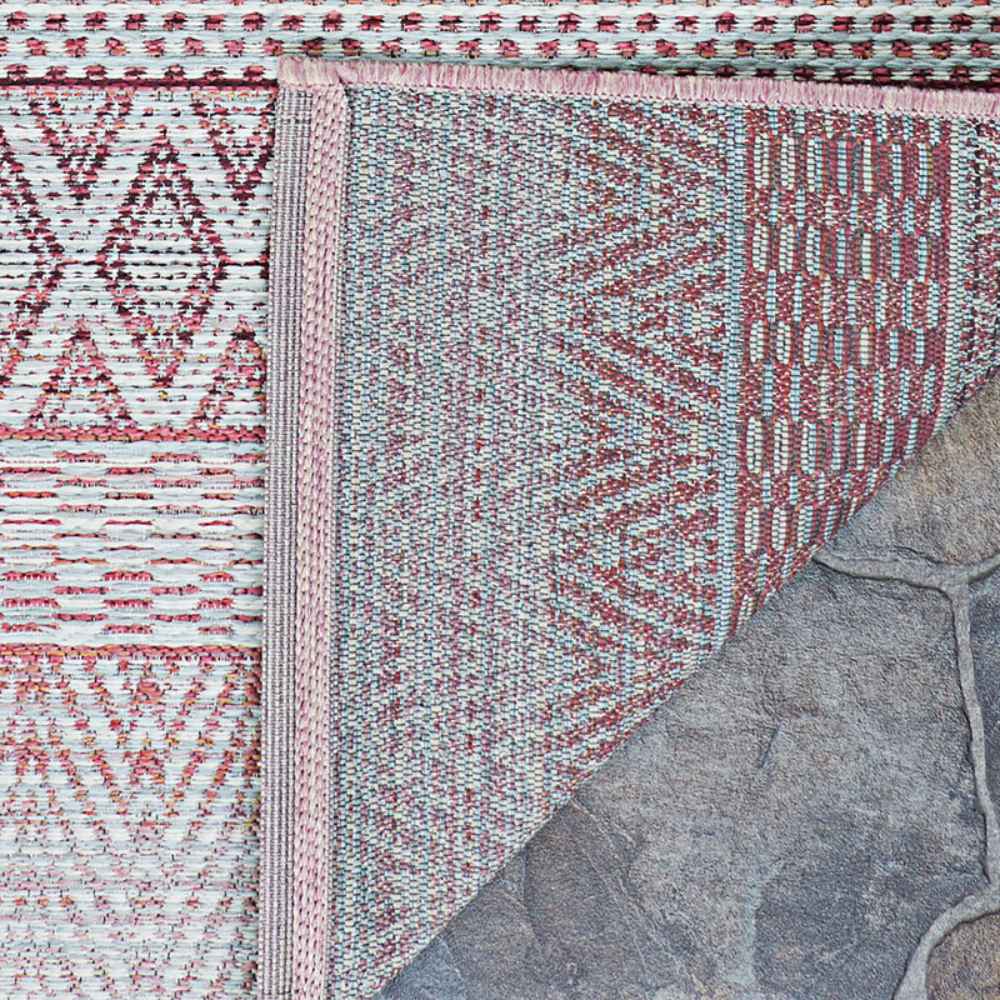 A corner of the Couristan Cape Indoor/Outdoor Rug - Gables/Hibiscus is flipped over to display the backside weave and clean edging details