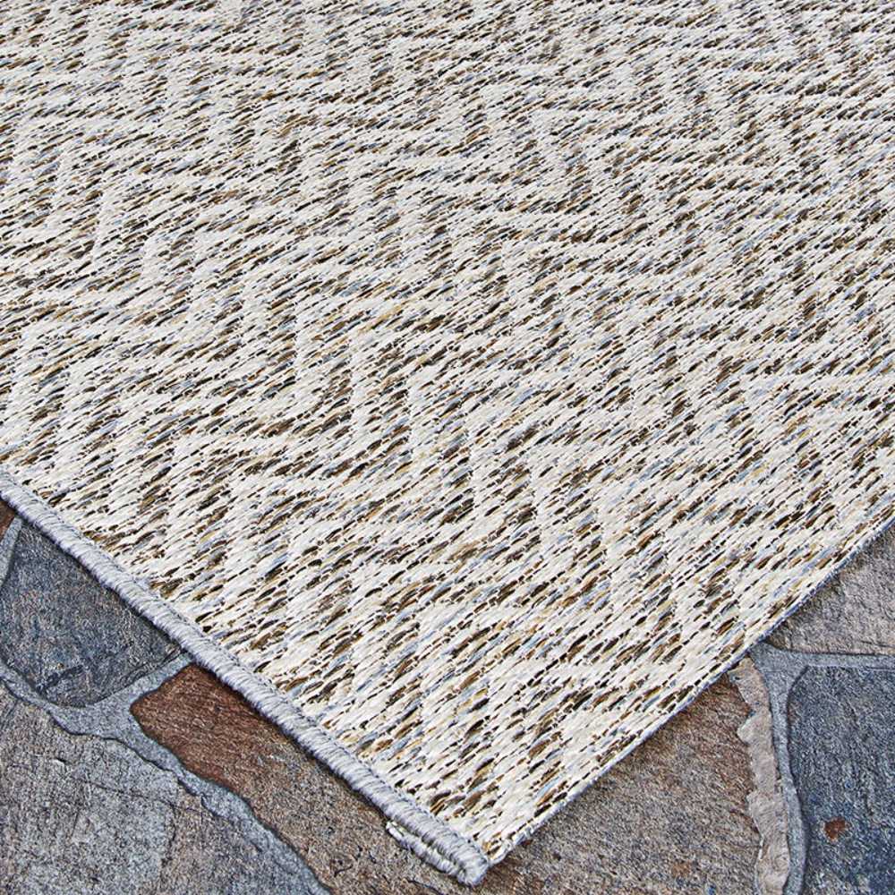 A corner of the Couristan Cape Indoor/Outdoor Rug - Marion/Light Brown-Ivory highlights its sturdy weave and clean edge resting on a rustic stone surface
