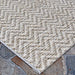 A corner of the Couristan Cape Indoor/Outdoor Rug - Marion/Light Brown-Ivory highlights its sturdy weave and clean edge resting on a rustic stone surface