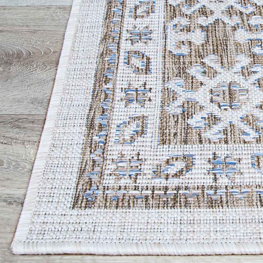 A corner of the Couristan Charm Indoor/Outdoor Rug - Woodburn/Ivory-Sand displays its tightly stitched edge and clean finish on hardwood flooring