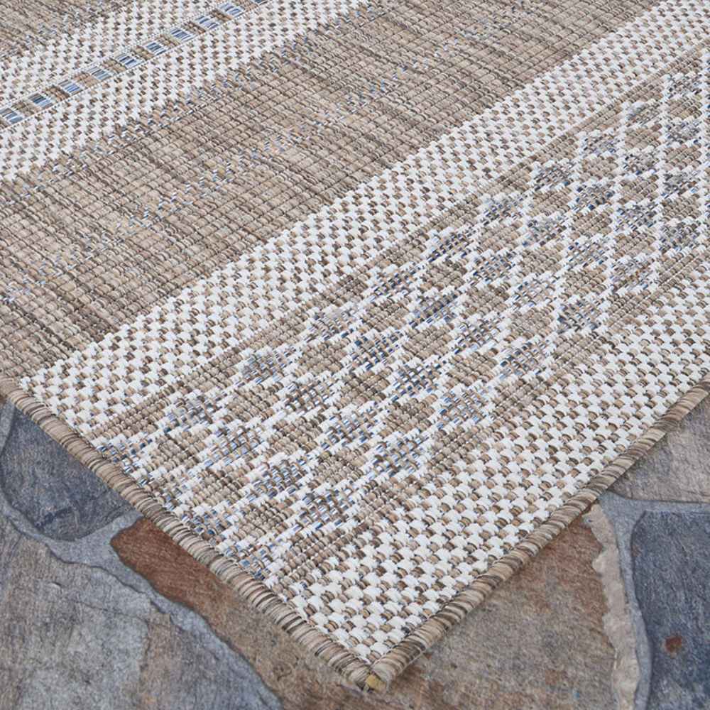 A corner of the Couristan Charm Indoor/Outdoor Rug - Yukon/Twig displays clean edges and a balanced blend of tan, ivory, and soft blue