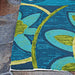 A corner of the Couristan Covington Indoor/Outdoor Rug - Rip Tide/Ocean-Green lies flat against stone pavers