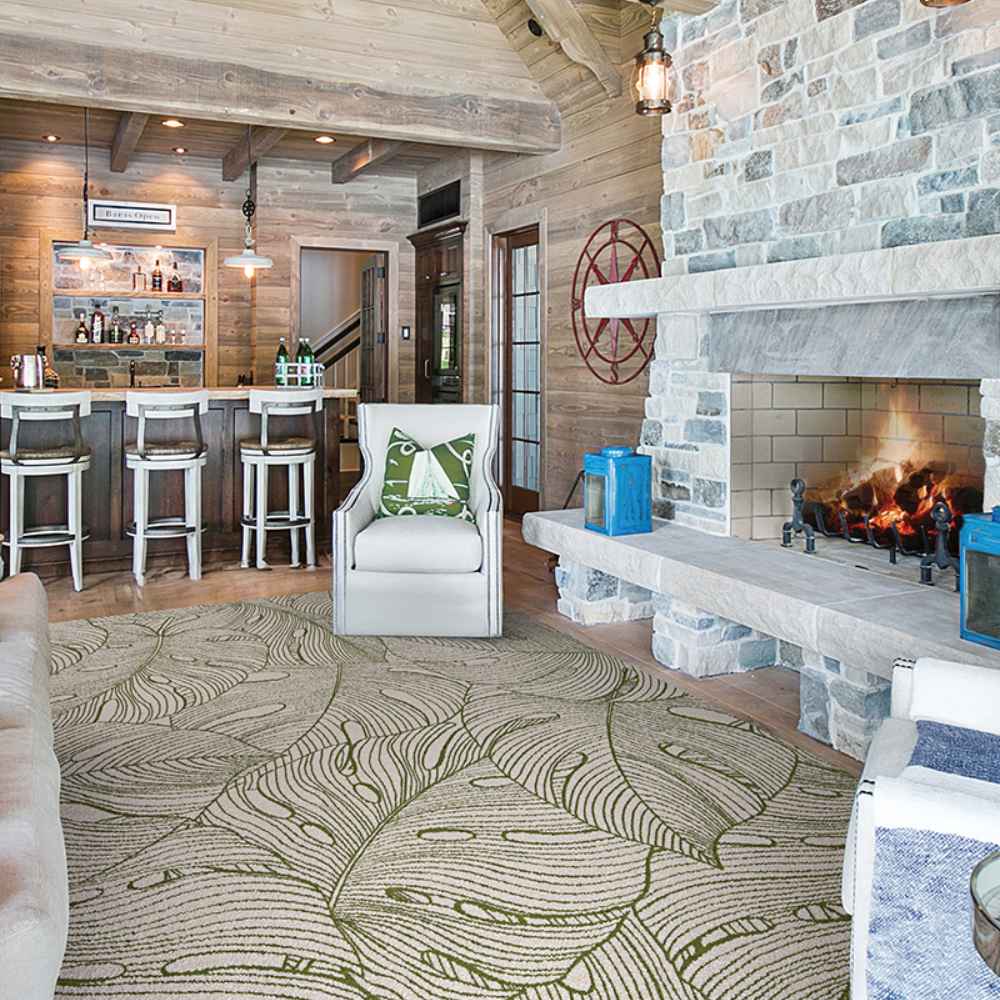 A cozy living room with wood and stone accents features the Couristan Castille Indoor/Outdoor Rug - Palma/Fern spread across the floor
