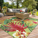 A cozy outdoor patio is styled with a rattan sectional and a vibrant Couristan Covington Indoor/Outdoor Rug - Painted Fern/Fern-Red featuring large tropical flowers