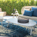 A cozy patio scene displays the Couristan Castille Indoor/Outdoor Rug - Canvas/Orion beneath modern outdoor furniture and lush greenery
