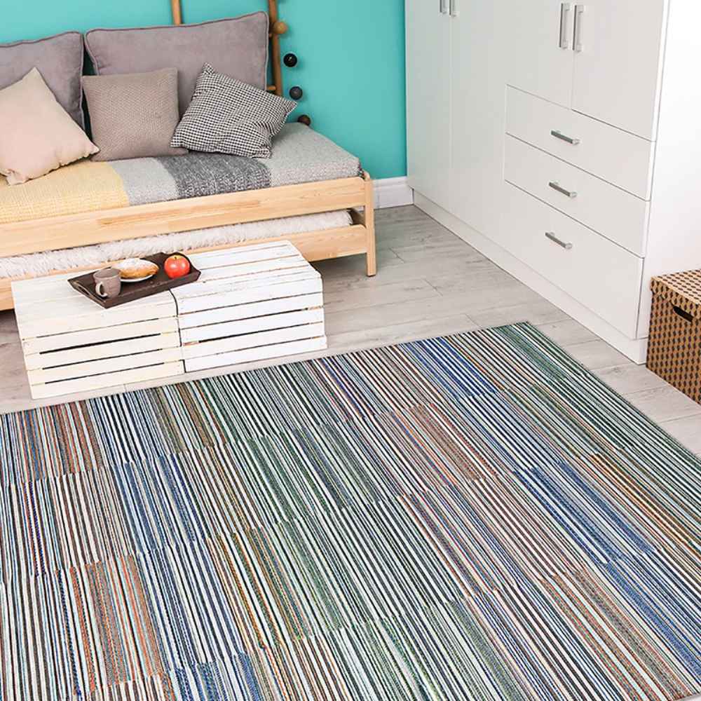 A cozy room features a colorful striped Couristan Cape Indoor/Outdoor Rug - Shoreham/Ivory-Multi laid on light wooden floors beside a daybed