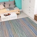 A cozy room features a colorful striped Couristan Cape Indoor/Outdoor Rug - Shoreham/Ivory-Multi laid on light wooden floors beside a daybed