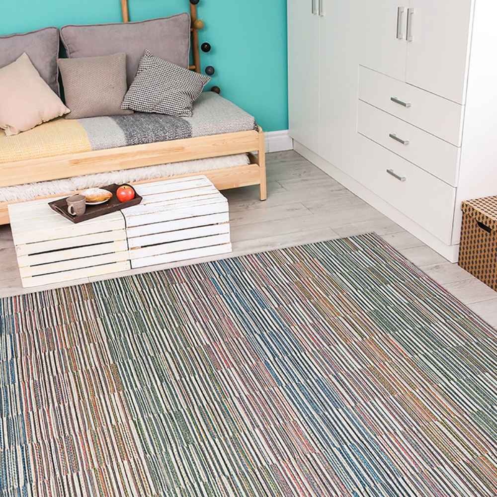 A cozy room with a daybed, teal wall, and white furniture features the Couristan Cape Indoor/Outdoor Rug - Fayston/Multi on the light wood floor