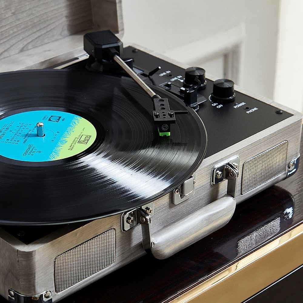 A detailed close-up of Arkrocket Curiosity Suitcase Bluetooth Turntable (Gray Wood Grain) shows the needle touching the vinyl record