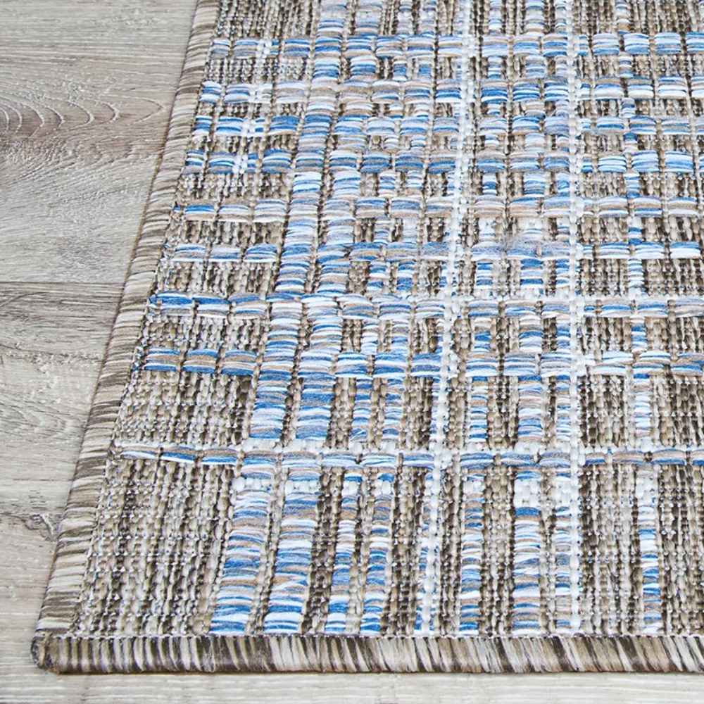 A detailed corner of the Couristan Charm Indoor/Outdoor Rug - Ohe/Sand-Ivory highlights the neatly finished edge and tightly stitched pattern