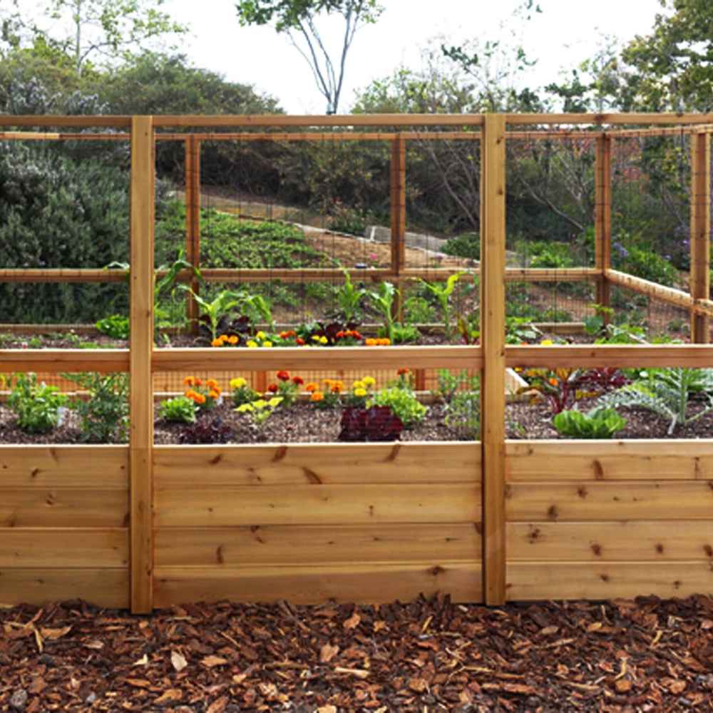 A front view of the Outdoor Living Today 8×12 Raised Garden Bed shows lush vegetables and bright flowers protected by mesh fencing and tall wood panels