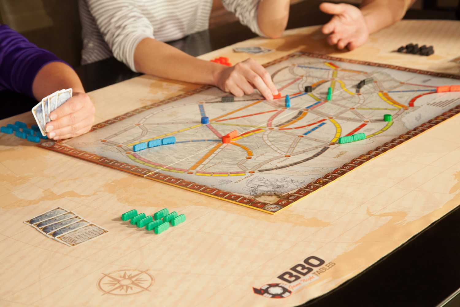 A game in progress on the BBO Poker Tables Portable Poker Party Mat - World Traveler displays vibrant pieces and cards atop the mat's map design