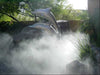 A garden with dolphin statues is filled with fog-like mist produced by the Aeromist Pinnacle 1000 PSI Misting System
