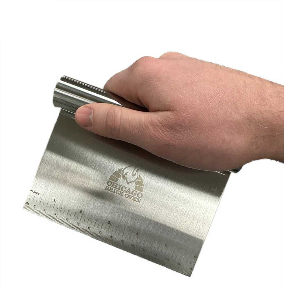 A hand gripping the Chicago Brick Oven 6 x 4 12 Stainless Steel Dough CutterScraper