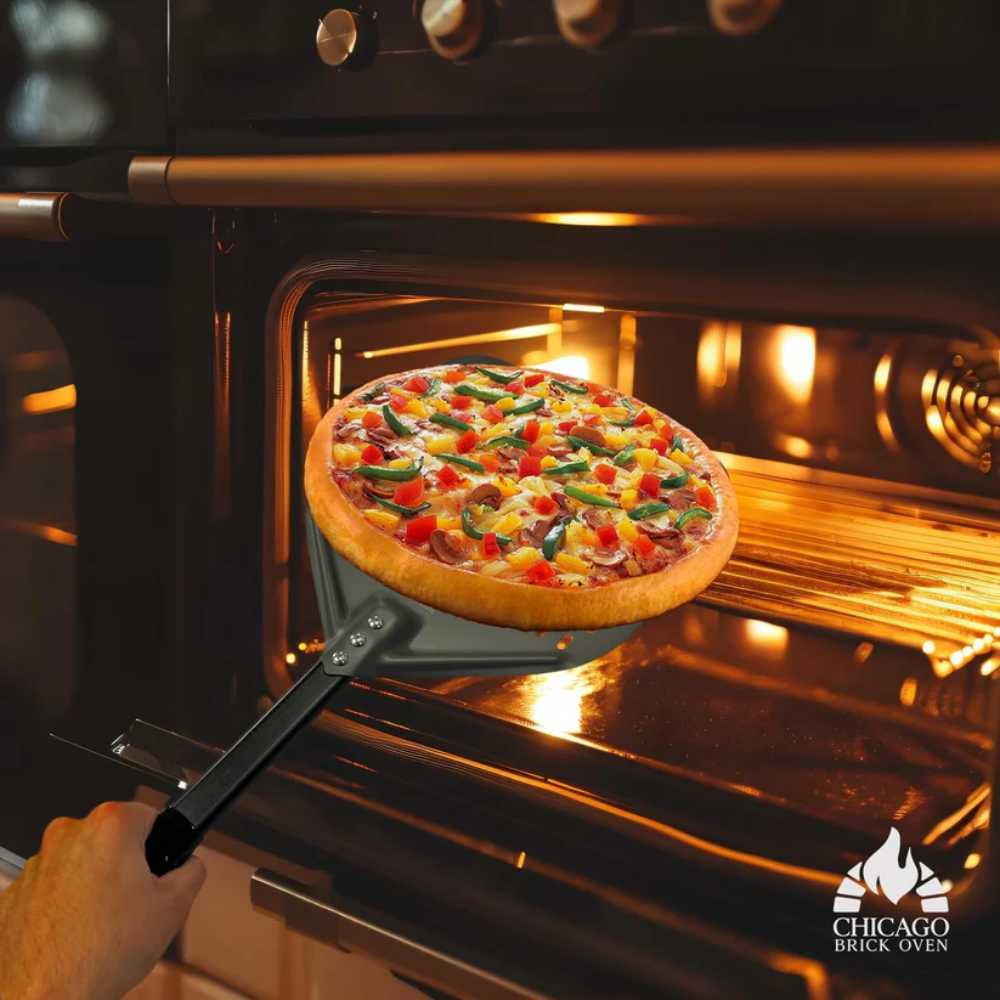 A hand using the Chicago Brick Oven 12x15 Perforated Pizza Peel to take a freshly baked pizza out of an oven