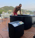 A man in red shorts is stepping into a Dreampod Ice Bath FLEX With Chiller on a rooftop deck, surrounded by scenic mountains